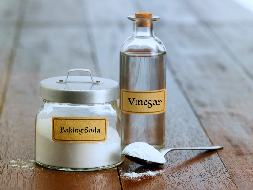 A bottle of vinegar next to a jar of baking soda and a spoon on a counter in this residential home in Carol Stream, IL.