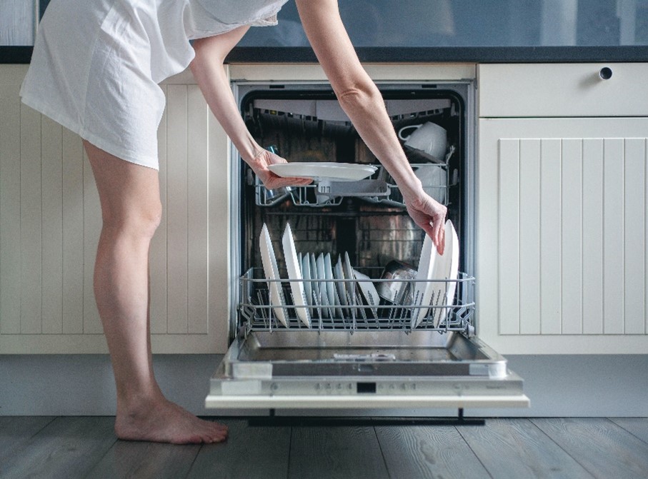 A female homeowner carefully loads her dishwasher in Carol Stream, IL, to ensure she is completing the process correctly.