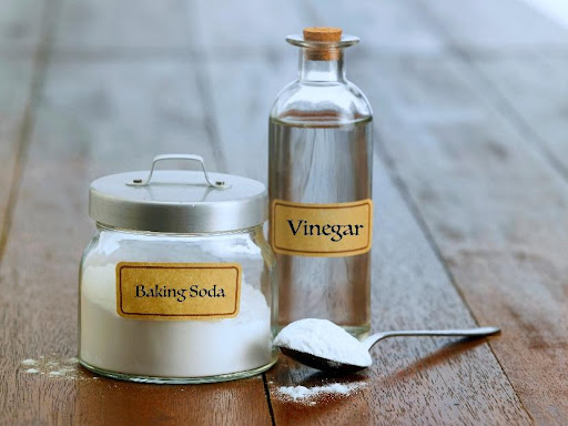 A bottle of vinegar next to a jar of baking soda and a spoon on a counter in this residential home in Carol Stream, IL.