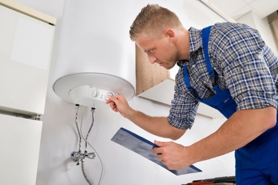 A plumber evaluating and adjusting a water heater in Chicagoland.