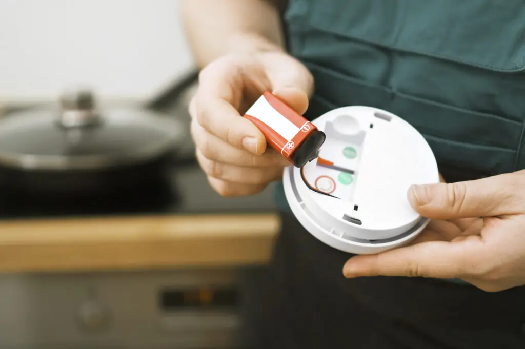 Person checking battery in smoke detector in the kitchen.